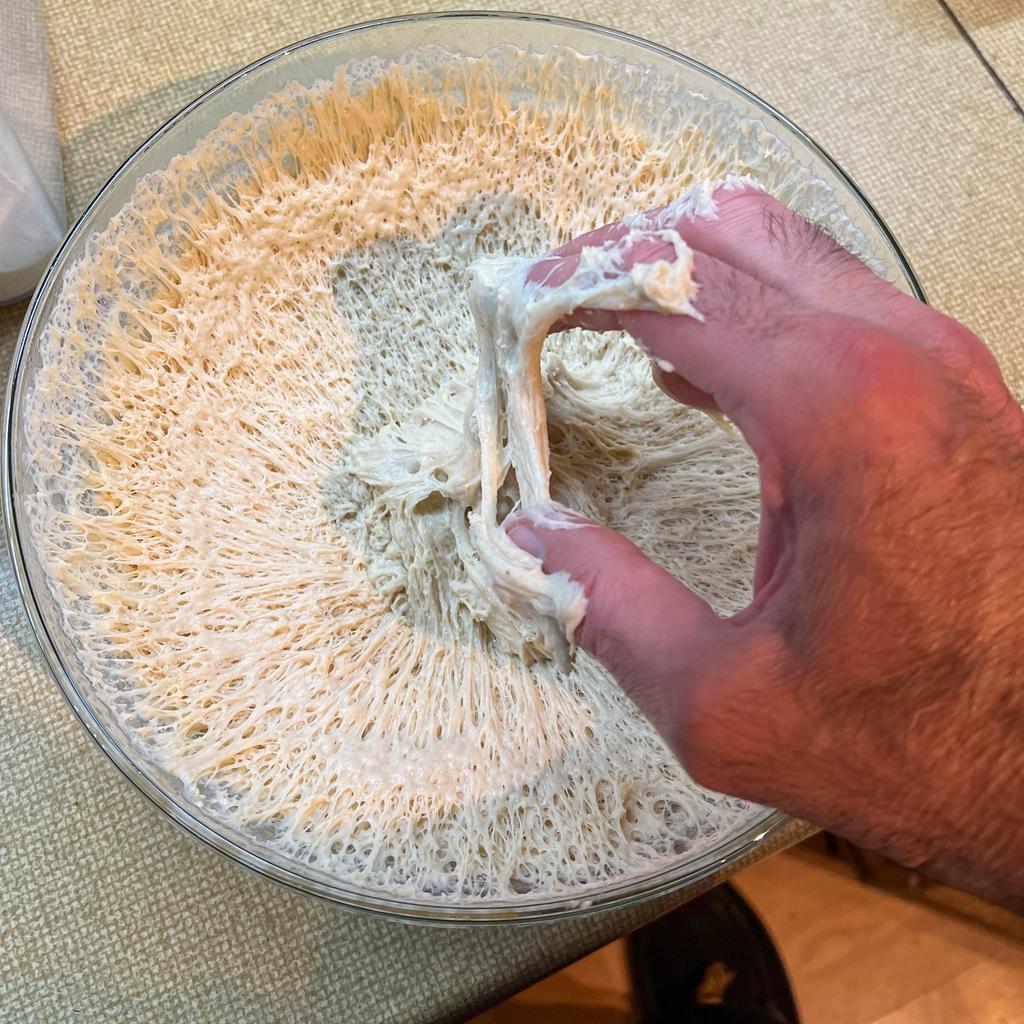 A bowl of bread dough after the first rise that I've unfortunately touched and now have stuck all over my fingers.