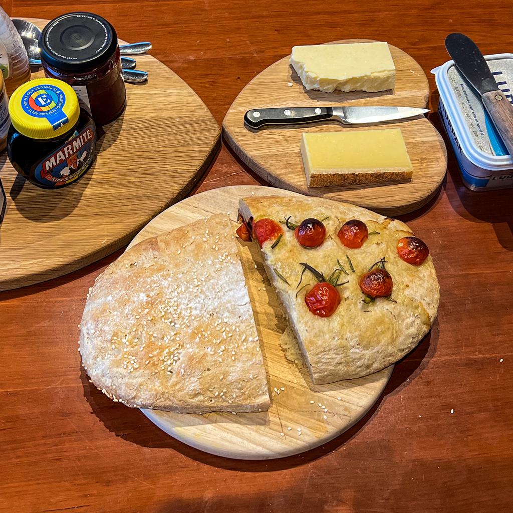 Two very flat loaves of bread with cheese and other accompaniments 