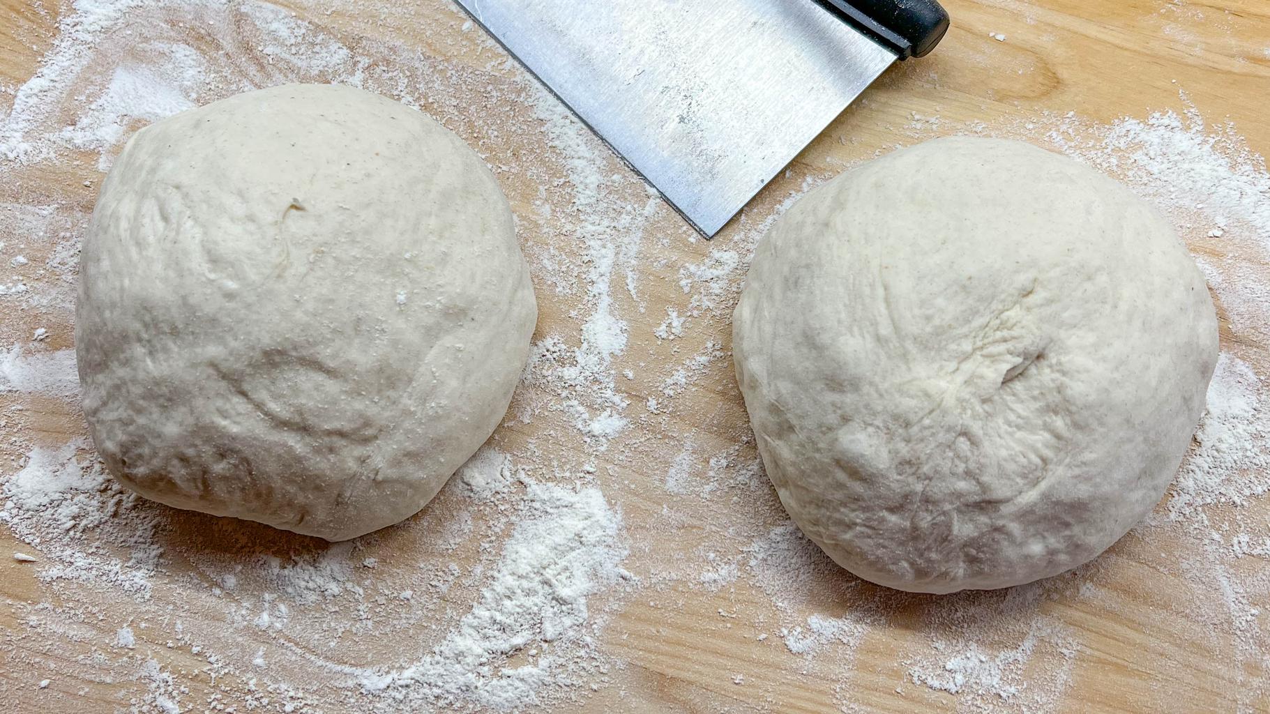 Two small balls of sourdough on a floured cutting board