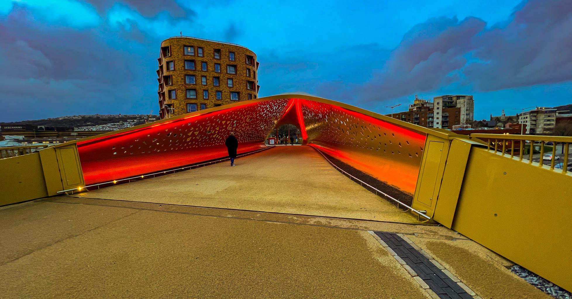 The pedestrian bridge over Oystermouth Road illuminated in red.