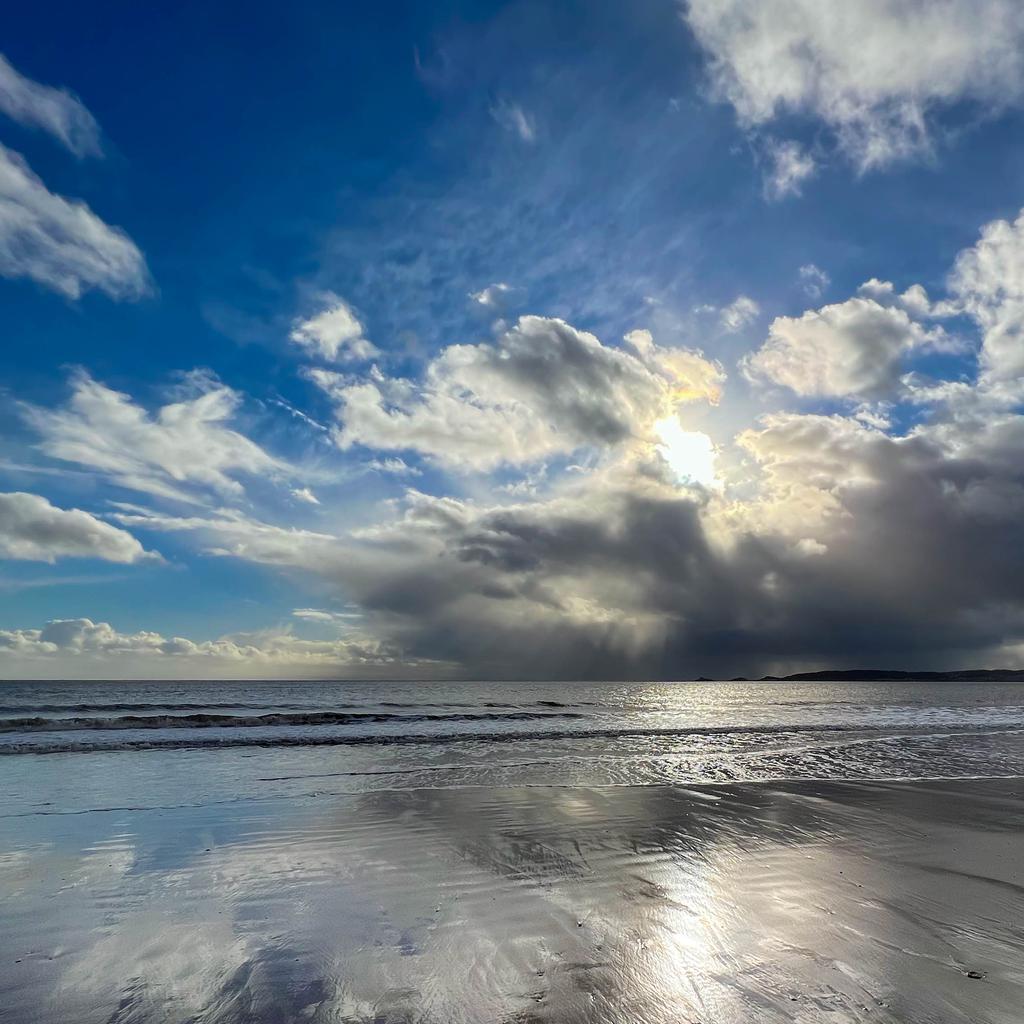 Swansea bay beach looking into the sun on a calm, sunny day.