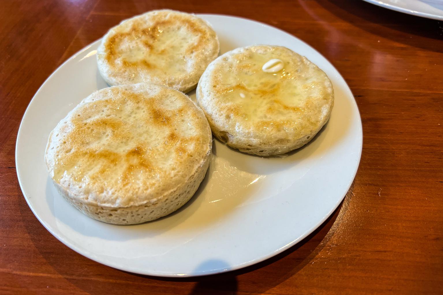 Three buttered sourdough discard “crumpets” on a plate.