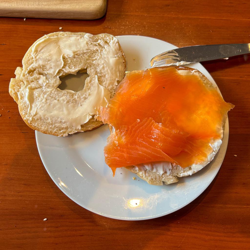 An open faced bagel "sandwich" smeared with cream cheese and topped with a slice of smoked salmon