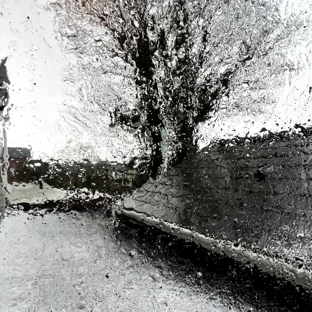 Mostly black and white photograph of wind and freezing rain blattering across the roof and into the window.
