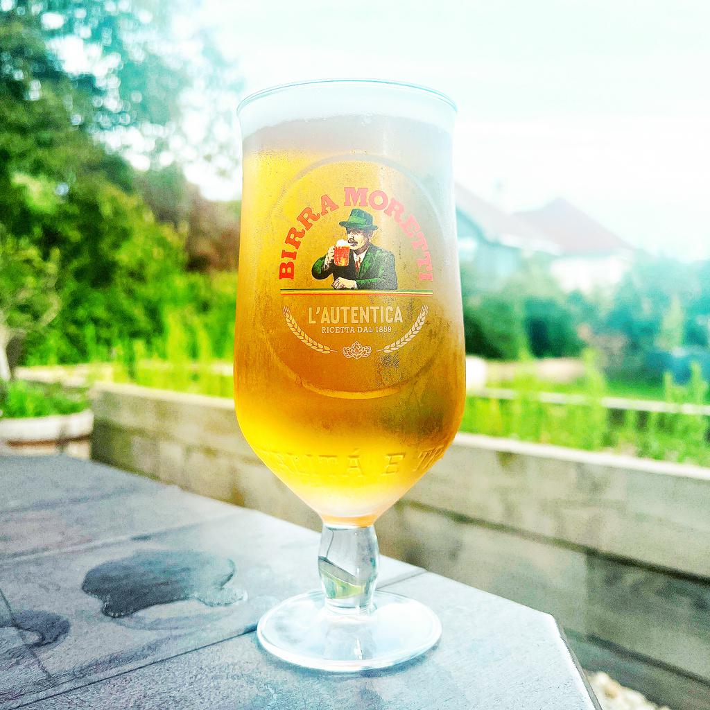 A cold glass of beer on an outdoor table.