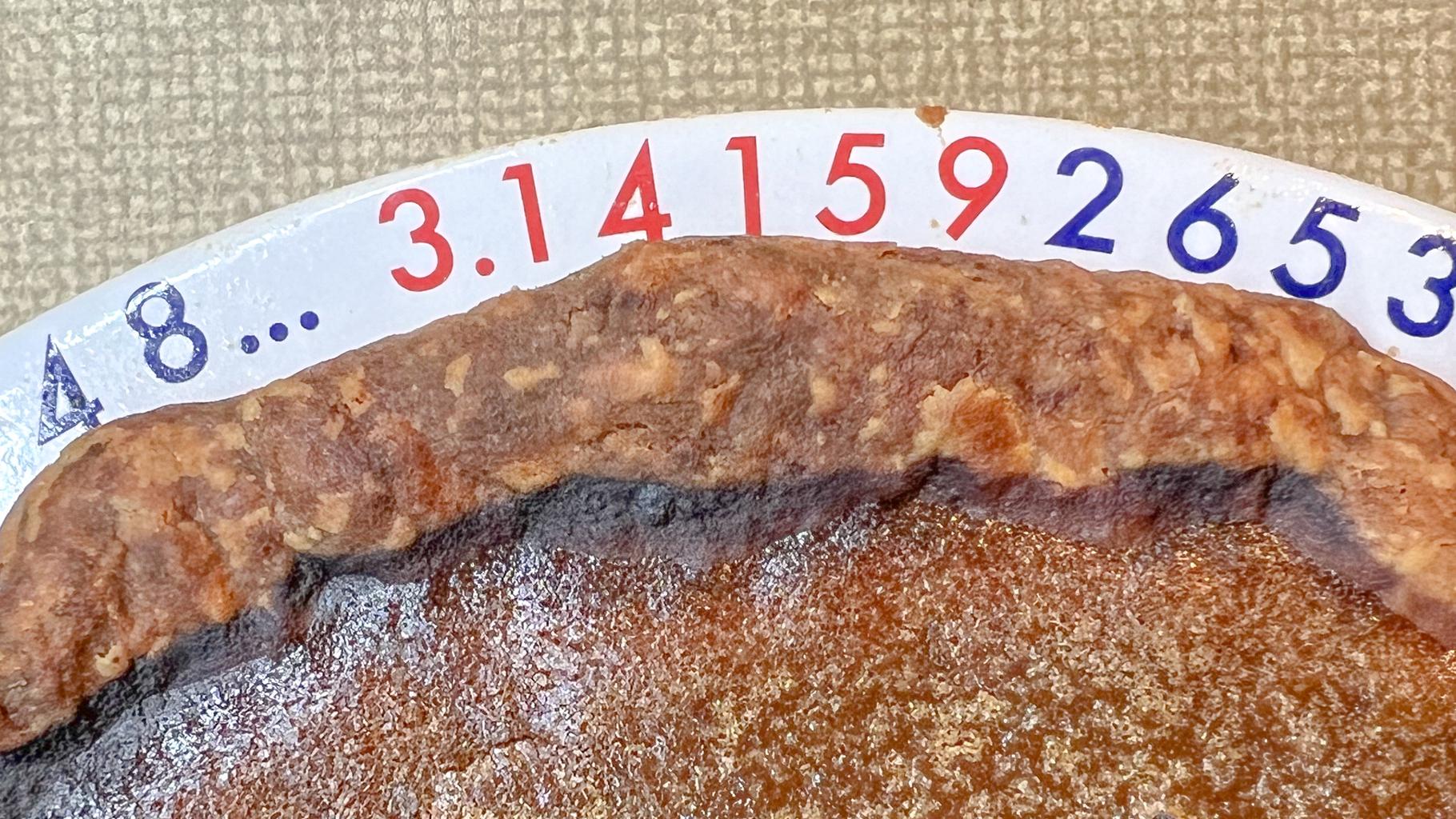 A slightly overdone pumpkin pie in a π plate (the digits 3.141592… are printed around the rim)