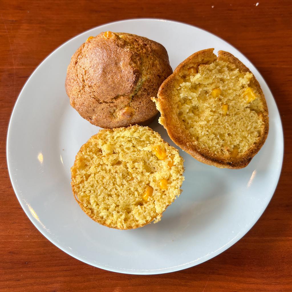 Two corn muffins on a white plate, one cut in half.